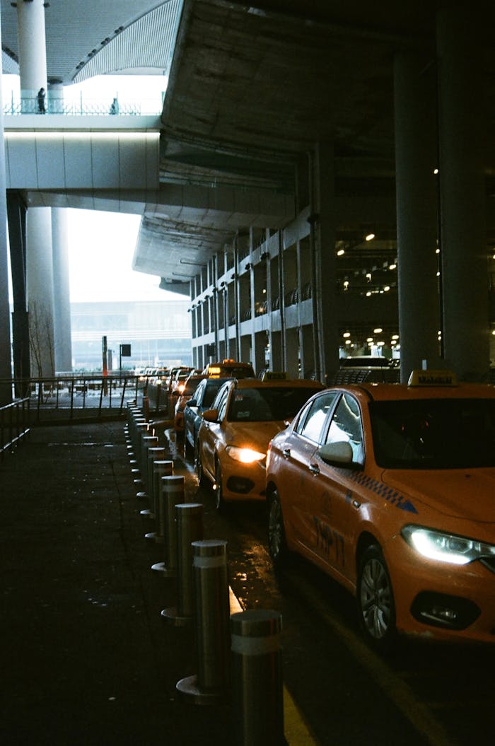 Orange taxis in line under a modern airport terminal showcase urban transportation.